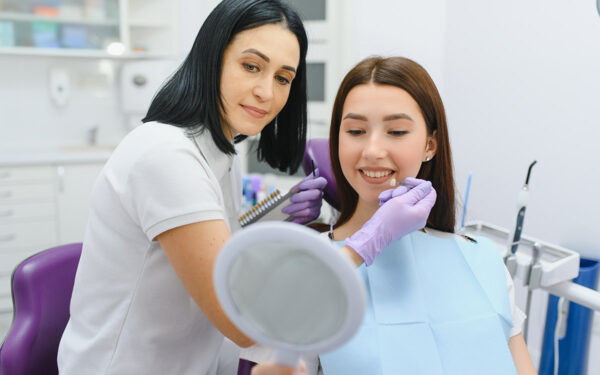 Young woman choosing color of teeth at dentist