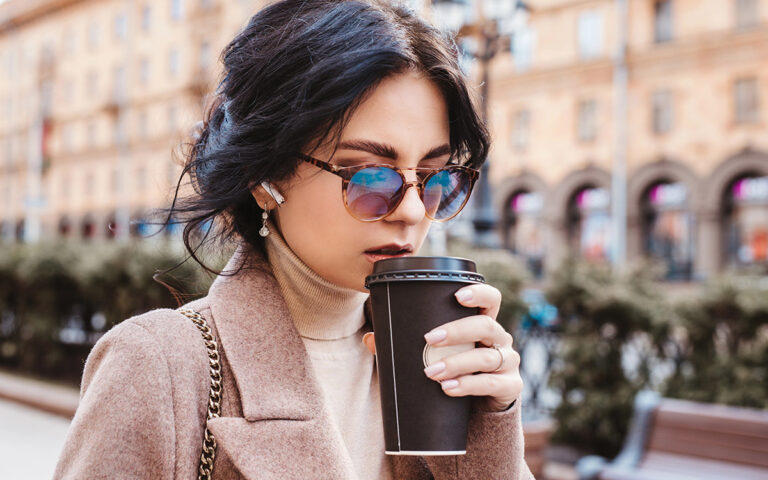 woman drinking coffee while walking in the street