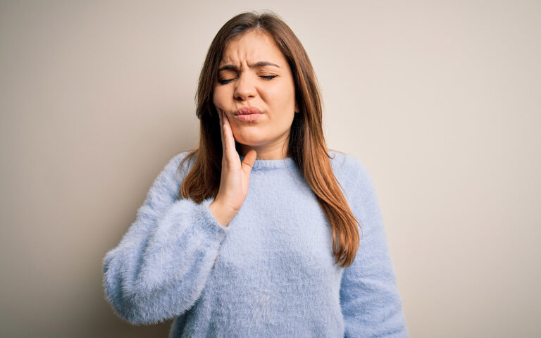 woman with tooth pain touching her mouth