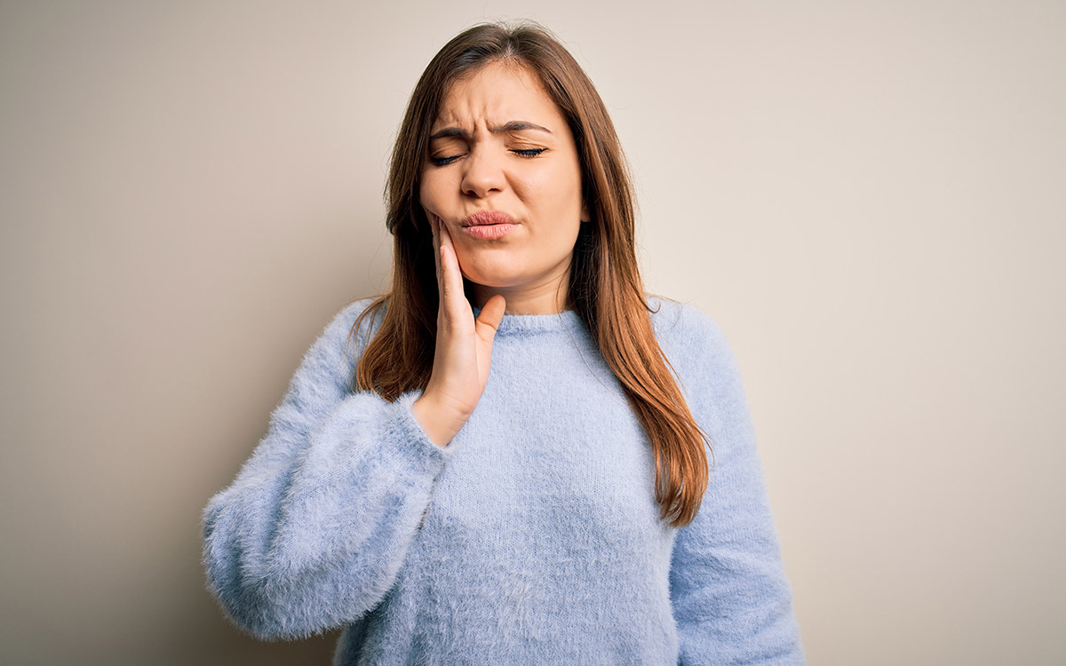 woman with tooth pain touching her mouth